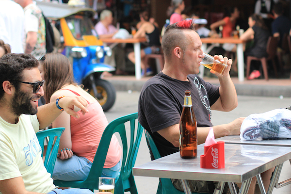 Tourist eating scorpion with beer