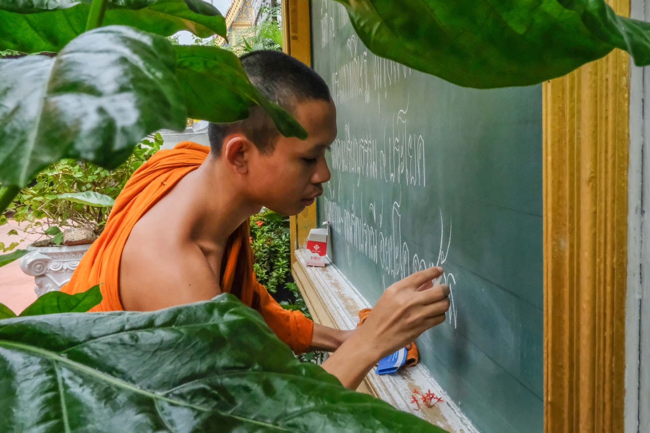 Monk writing on chalkboard